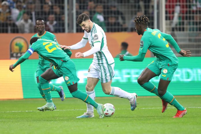 أيمن محيوص في صراع على الكرة بين لاعبين اثنين من منتخب السنغال